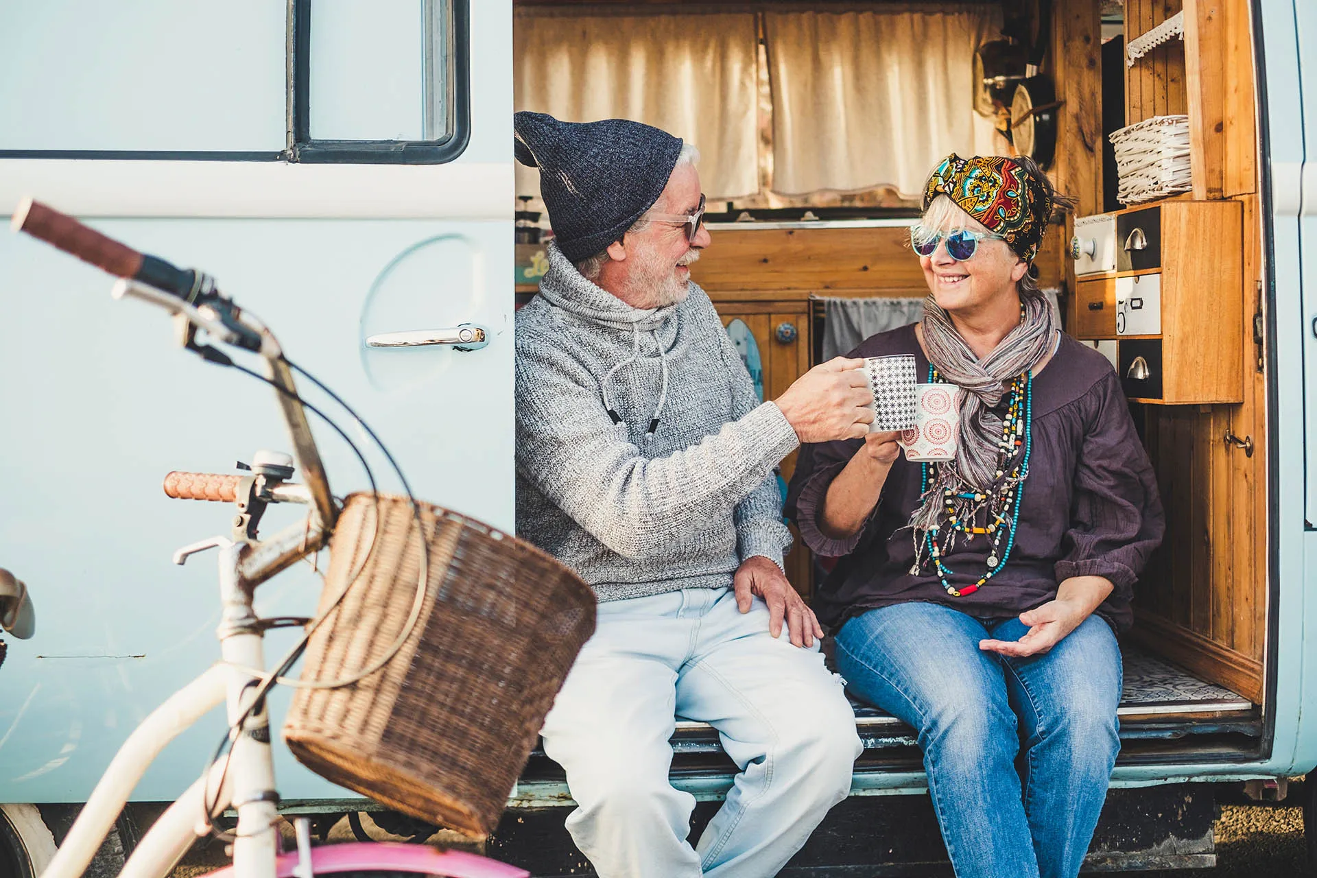 man and woman having tea in camper door 